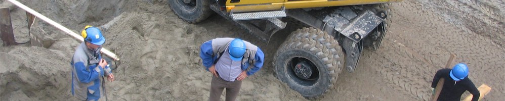 Trabalhadores com capacetes e uniforme em área de terraplenagem